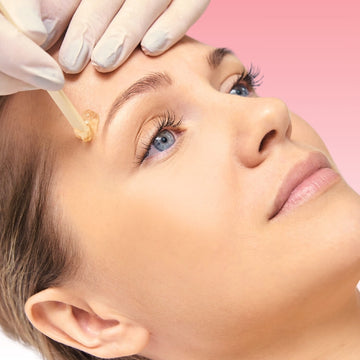 Esthetician shaping and waxing a client’s eyebrows for a clean, defined look.