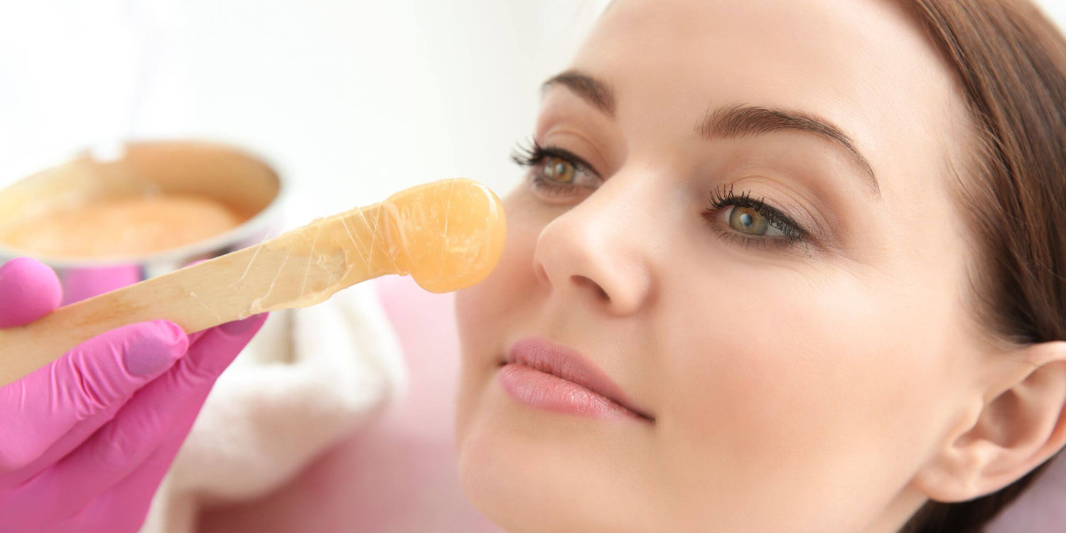 Esthetician shaping and waxing a client’s eyebrows for a clean, defined look.